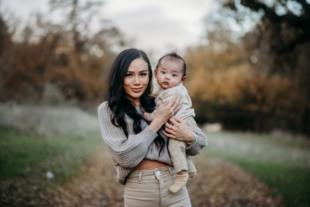 a cloudy day family photography session in pleasanton. a mom holds her baby and the fall colors are soft behind them.