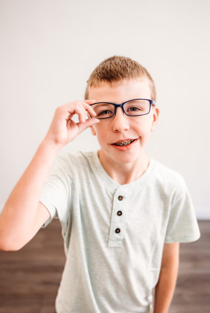 older child showing off his new glasses in his studio session