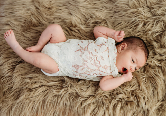 a newborn studio portrait of a baby in a lacy romper