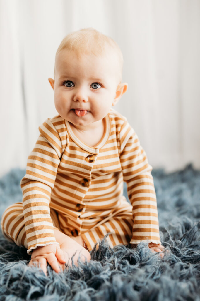 baby in martinez studio sticks out tongue and looks at the camera during his photography session