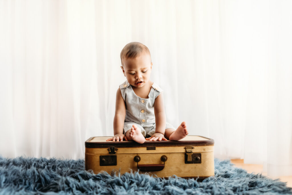 baby sitting on a suitcase prop during a studio photo shoot