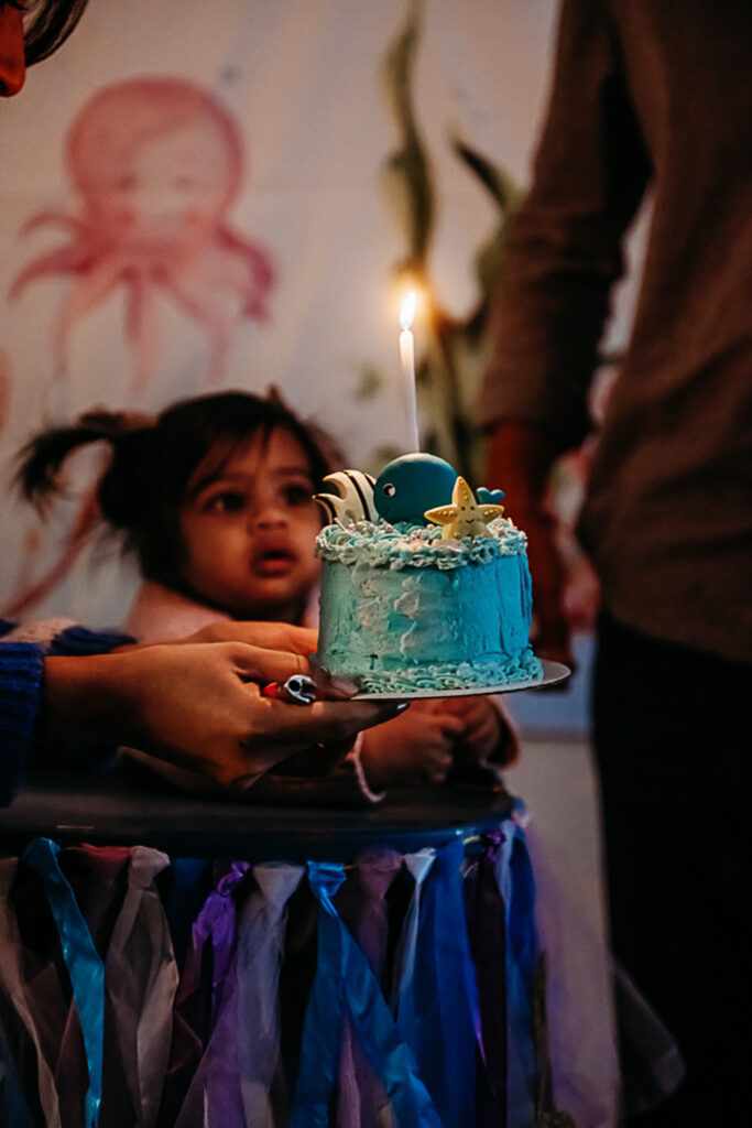 baby looking at the candle on her first birthday cake prior to her cake smash!