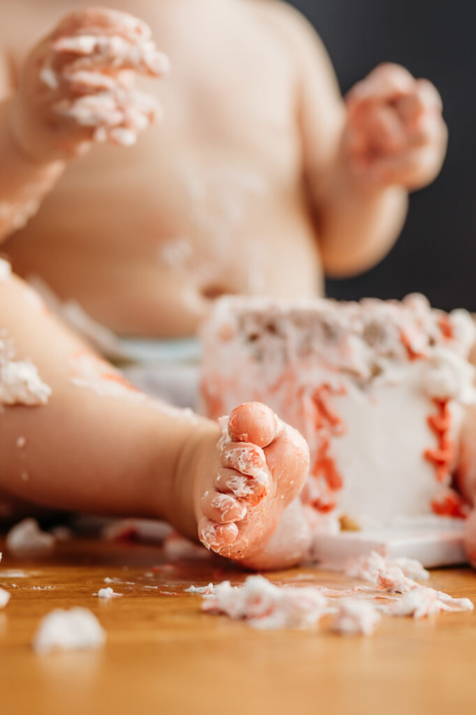 close up of cute messy toes covered in frosting from his cake smash photography session