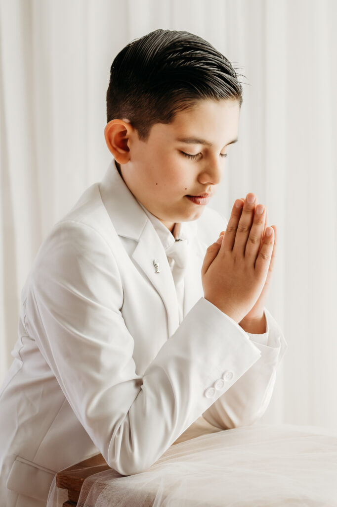 boy looking down praying during a first communion studio session