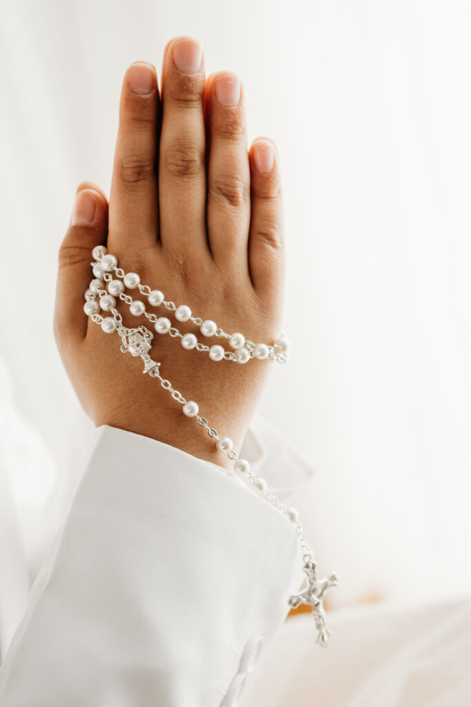 detail photo of praying hands with rosary for a first communion photoshoot