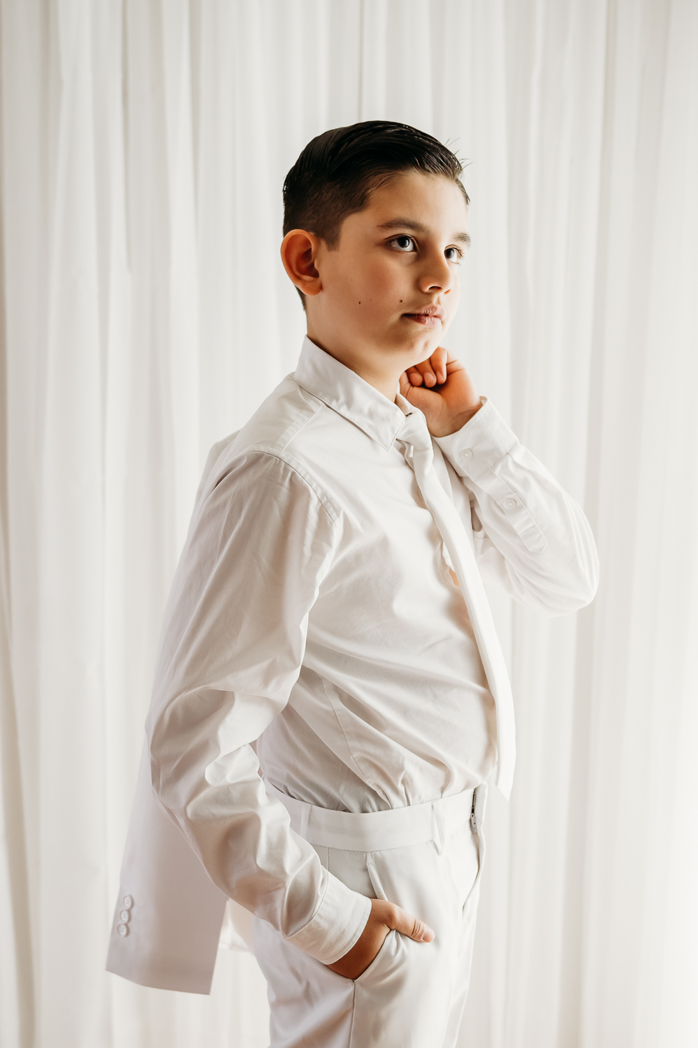boy in white suit holding his jacket over his shoulder