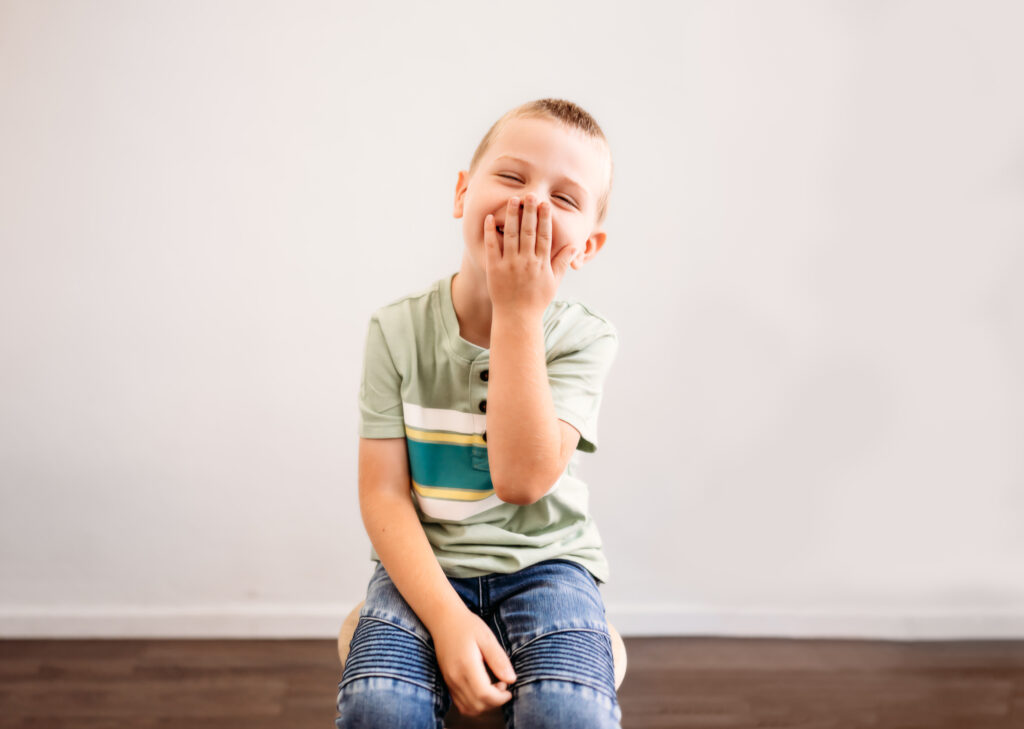 boy laughing covering his face during his photoshoot