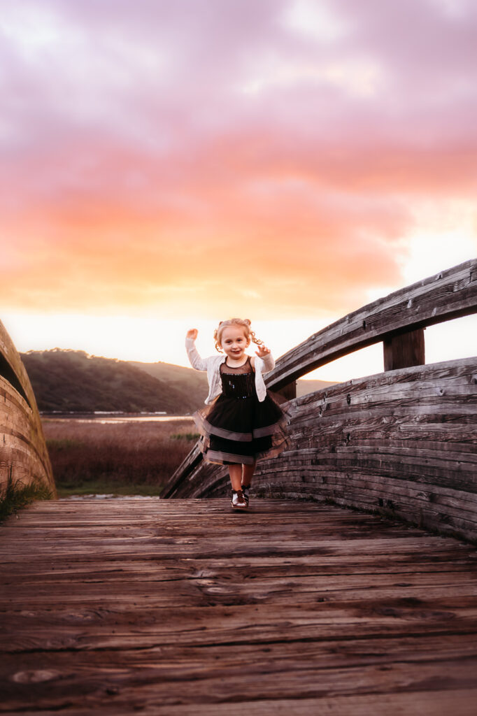 toddler running up the arch bridge in martinez under a colorful marina sunset