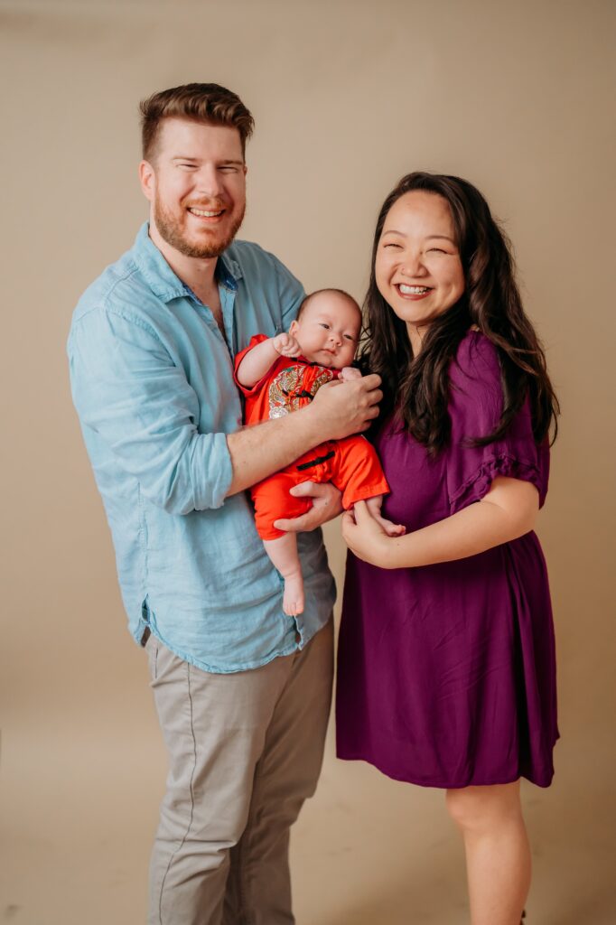 parents holding their 100 days baby  during their studio photo shoot