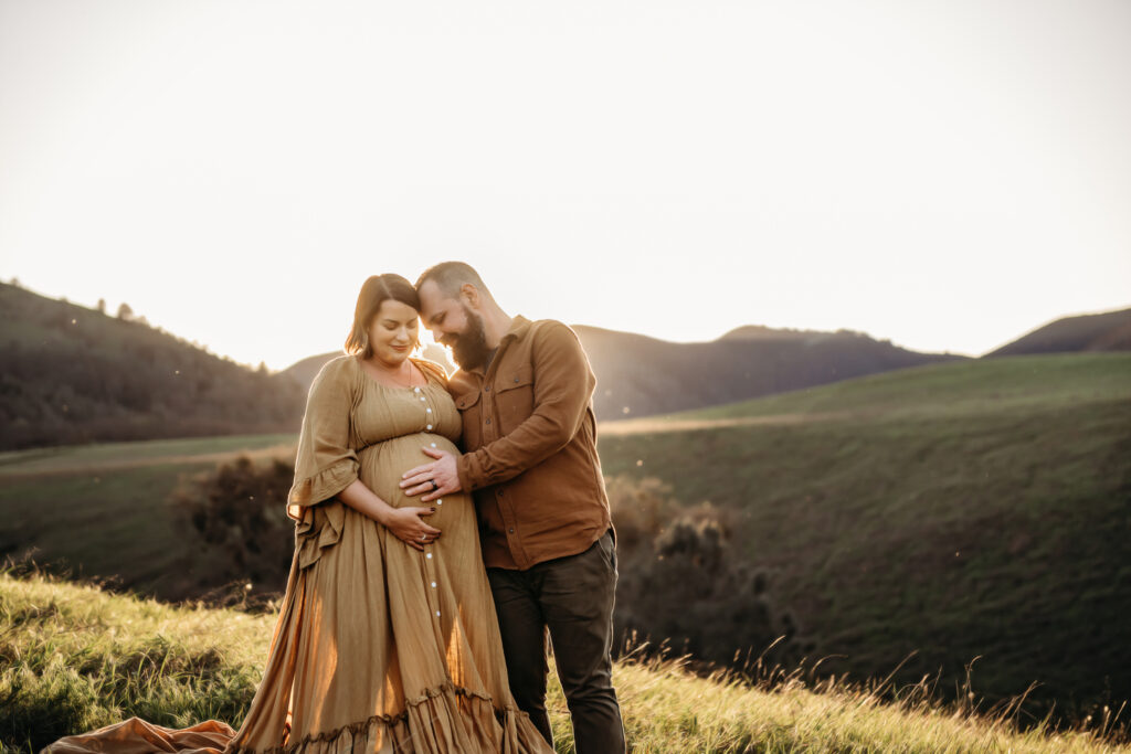 intimate maternity photo of husband and wife. they both look down at her belly.