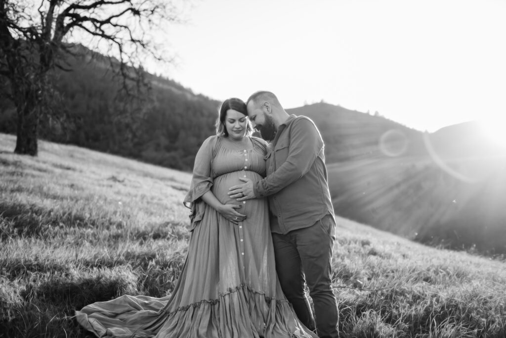 black and white photo of a couple with hands on mamas pregnant belly.