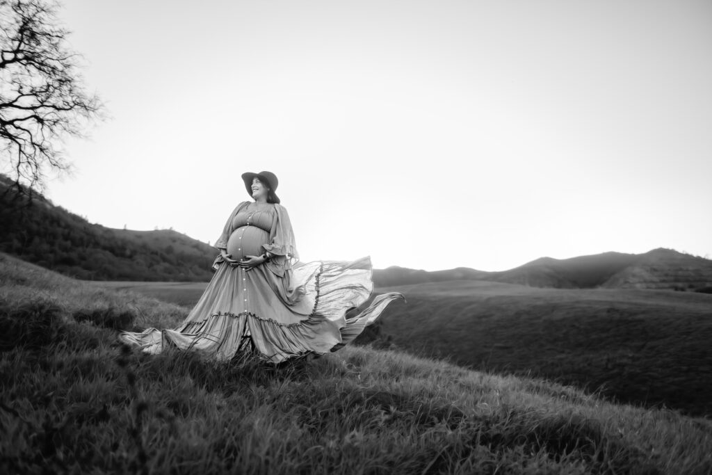 black and white photo of a pregnant mama. her flowing maternity dress blows in the wind.