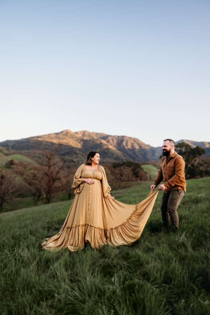 husband helps wife into position during their maternity session.