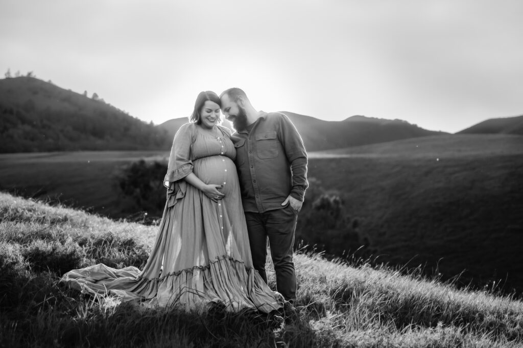 black and white photo of a couple. the woman is pregnant and they are both looking down at her belly