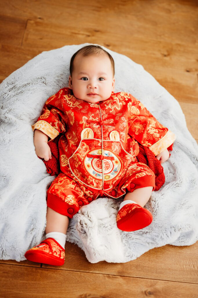 100 days old baby photo shoot. baby is in red and gold vietnamese outfit