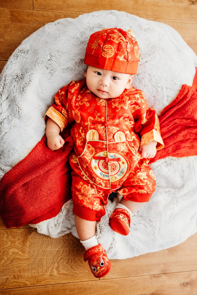 100 days old baby for traditional photo shoot. baby is in vietnamese outfit, with hat and booties.