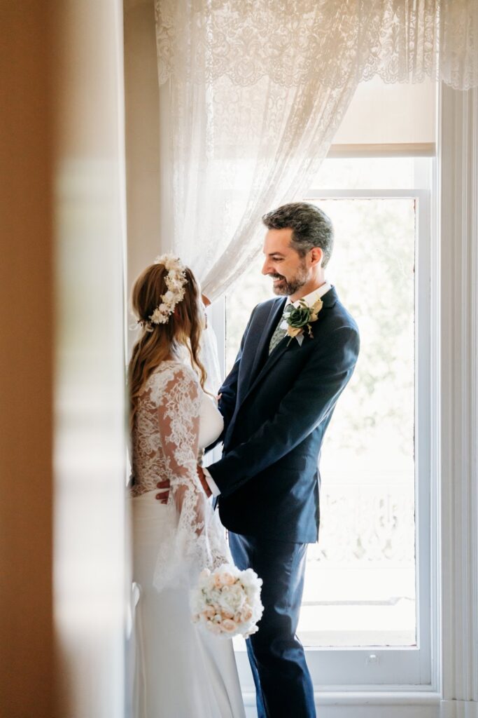 Newly married couple smiles at each other around the corner