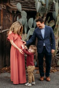 toddler laughs as he tickles his moms pregnant belly