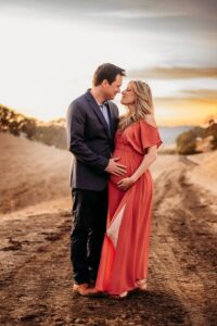 couple posing for maternity photos at the top of old borges ranch as the sun sets