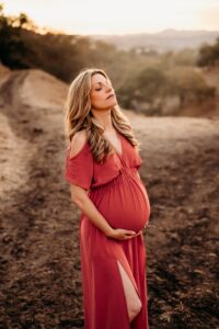 pregnant mom closes her eyes and leans back. she holds her belly below her baby bump