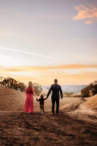 family holds hands and walks down the old borges ranch trail system as the sun sets.