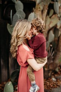 toddler cuddles his mama at their family photos. you can see the old borgess ranch's cactus behind them