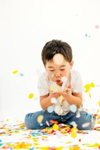 boy blows confetti at camera