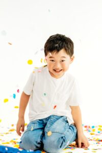 boy smiles surrounded by rainbow confetti