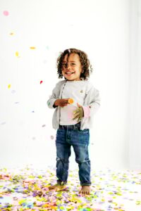 toddler surrounded by rainbow confetti in studio