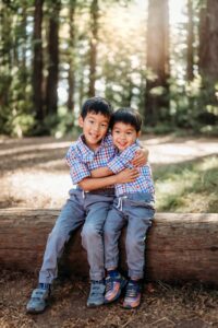 2 boys hugging while sitting on a redwood log