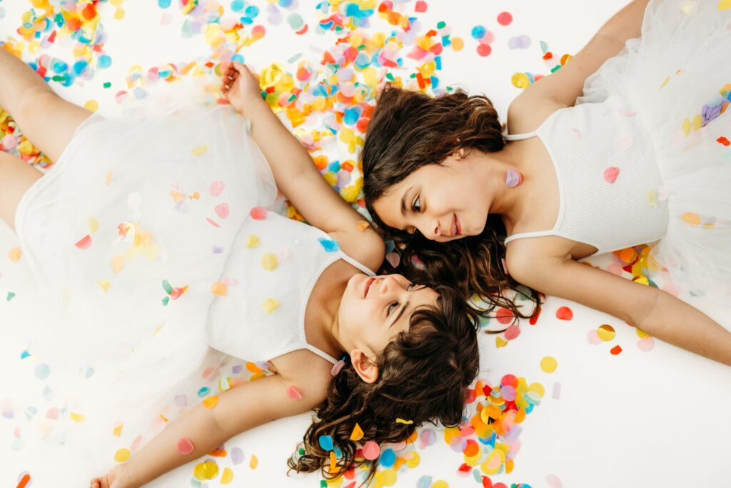 2 sisters laying in photography studio covered in rainbow confetti
