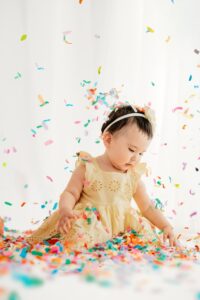 baby touches rainbow confetti as it falls in the studio