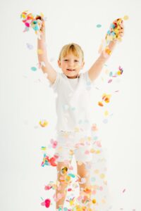girl in all white drops rainbow confetti
