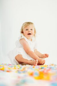toddler looks happily at camera while surrounded by confetti