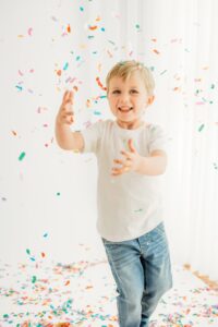 boy dancing around photography studio trying to catch confetti
