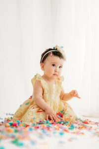 baby plays with confetti during her sisters birthday mini session