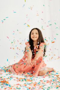 girl in pink dress catches confetti as it falls
