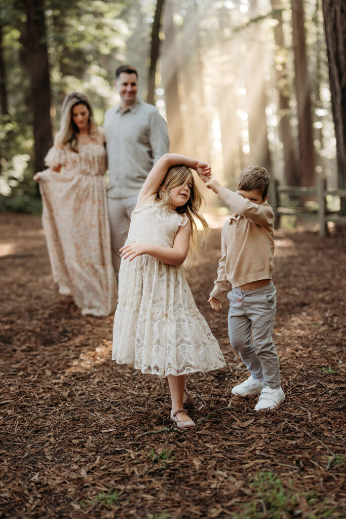 brother and sister dancing together with parents in the background