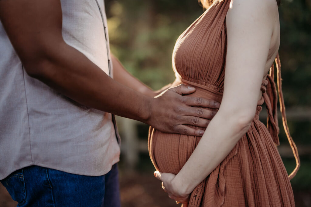 close up of mans hands on his pregnant wifes belly