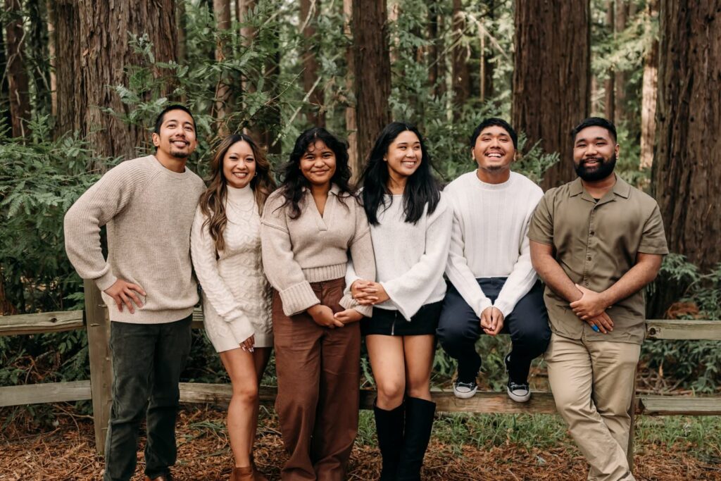 cousins sitting on a fence in a redwood forest