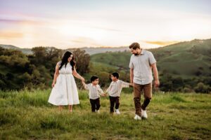 family of 4 walking in a line at the end of their photoshoot. the lafayette hills are seen behind them.