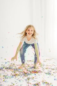 little girl bending over to pick up a handful of confetti at a walnut creek photography studio