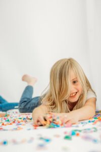 girl lays on her tummy gathering tons of confetti to throw around the photography studio