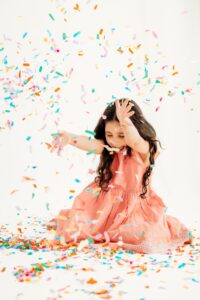 toddler yells happily as confetti falls on her head