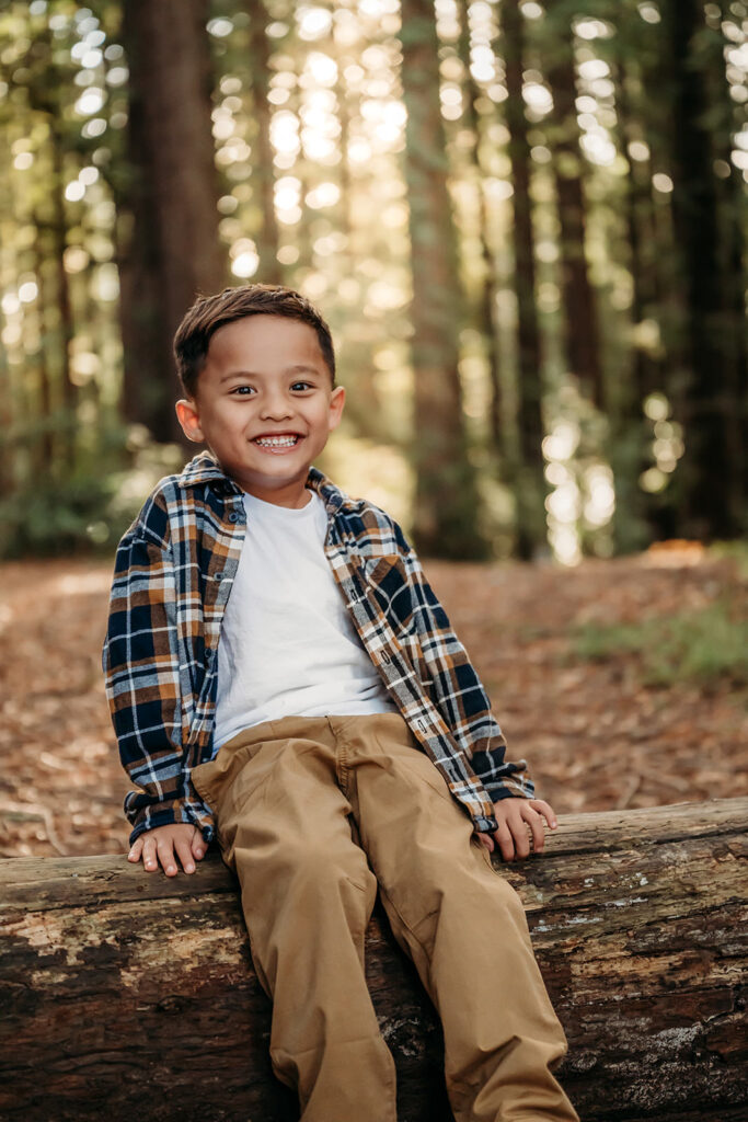 boy on redwood log with adorable cheesy smile