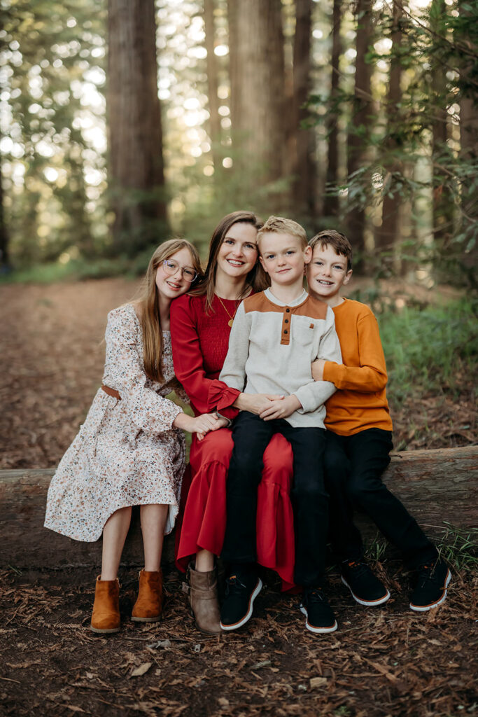 mom poses on a redwood log with her daughter and 2 sons. 