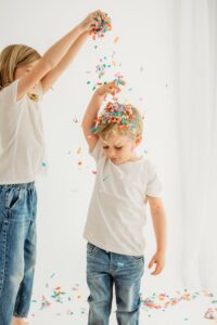 sister lets confetti fall on brothers head