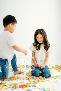 girl closes her eyes as brother throws confetti at her