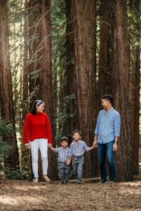 mom dad and 2 sons walking through a forest full of redwoods