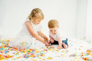 little girl piles confetti on her baby brothers foot